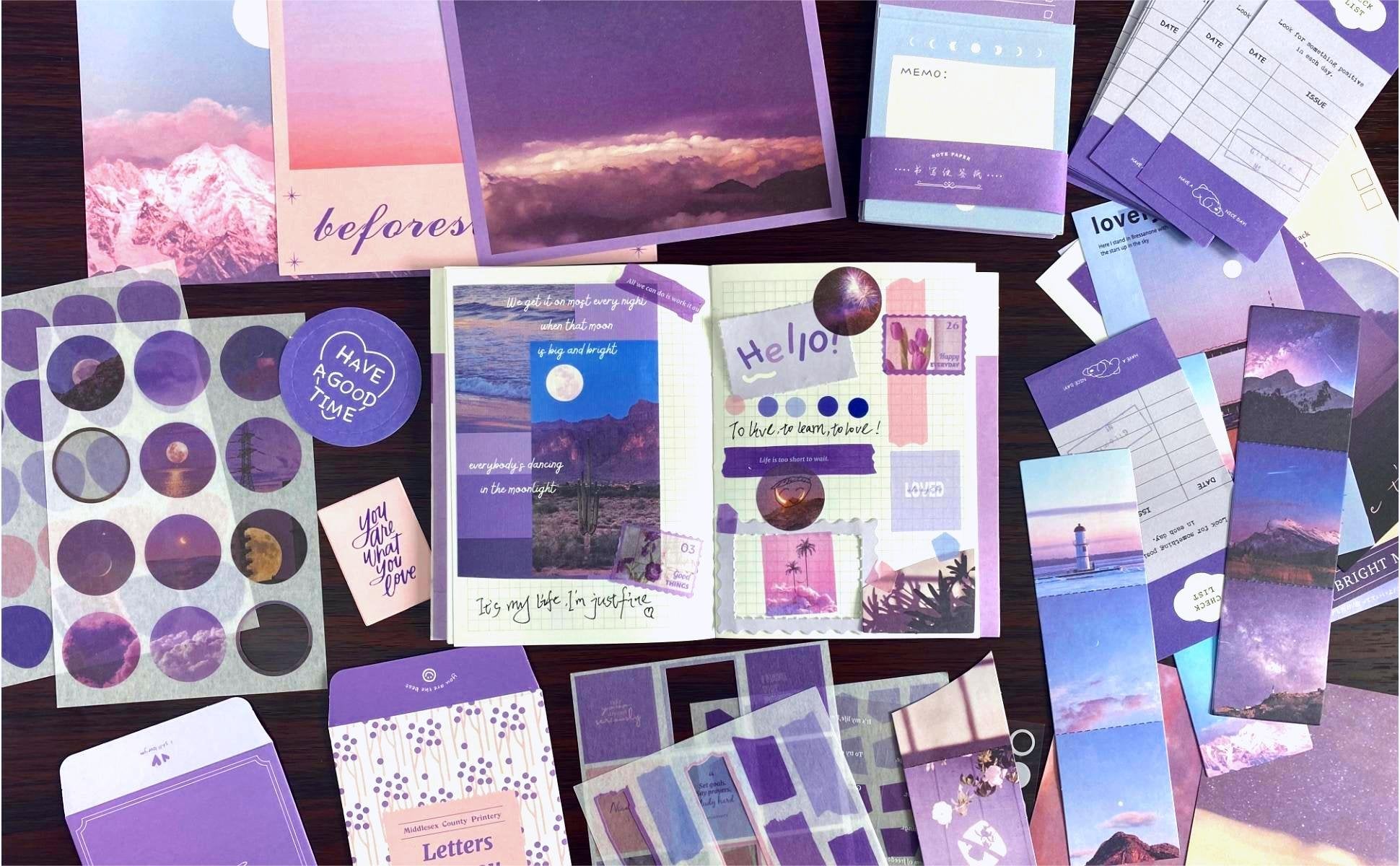 Aesthetic scrapbook kit contents including a notebook, stickers, envelopes, and journaling papers in shades of purple and pink.