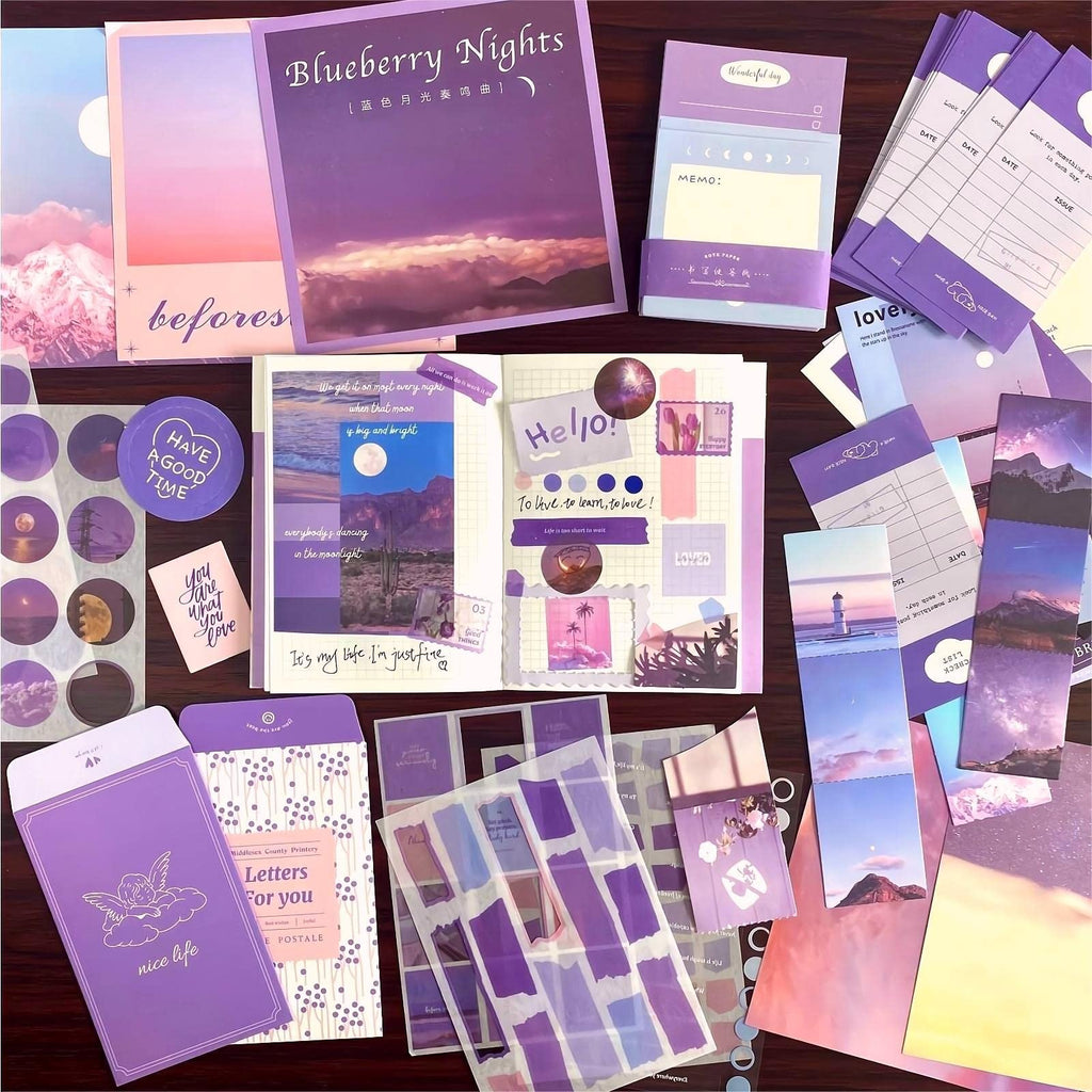 Aesthetic scrapbook kit contents including a notebook, stickers, envelopes, and journaling papers in shades of purple.