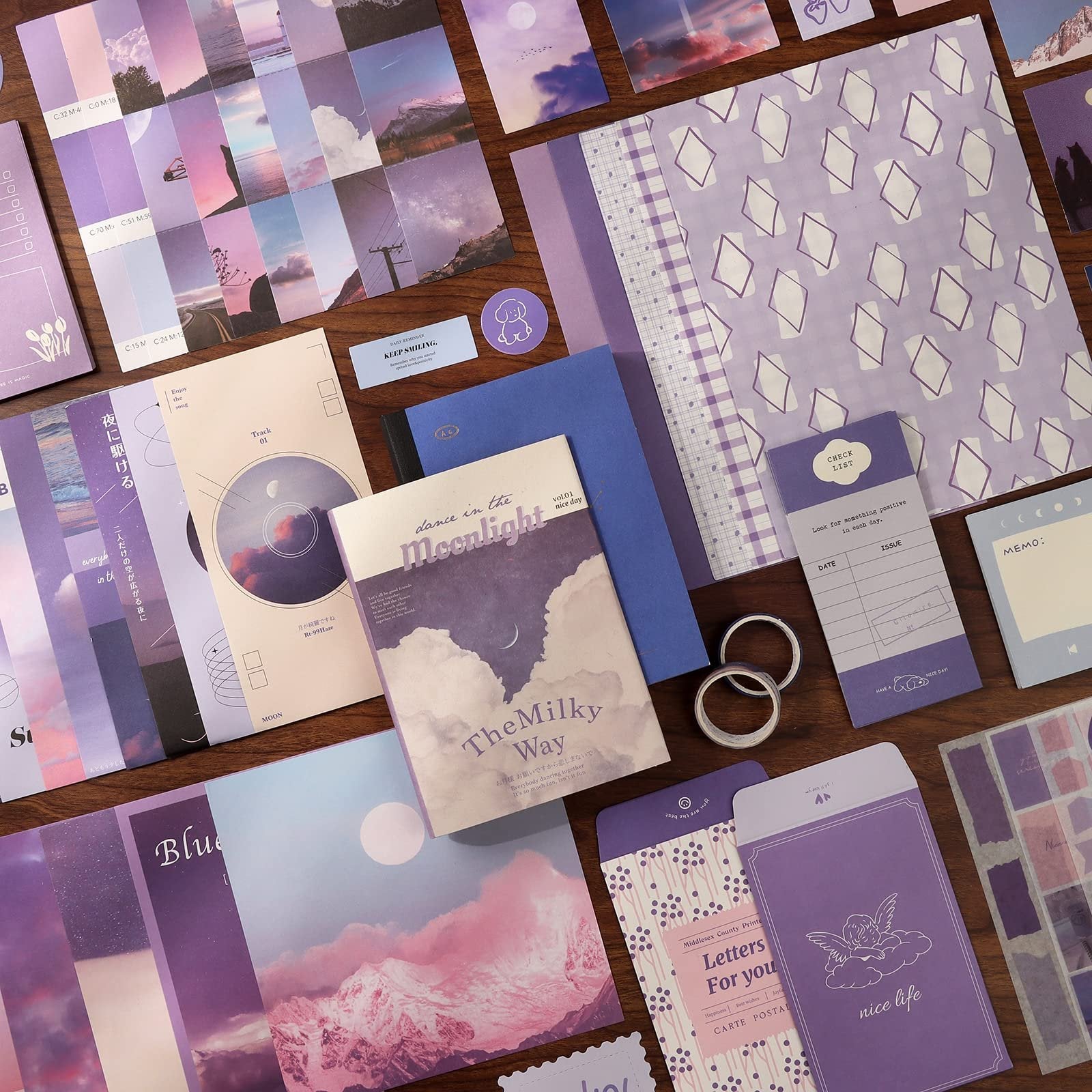 Aesthetic scrapbook kit contents including notebooks, stickers, washi tape, and decorative paper in purple and pink tones.