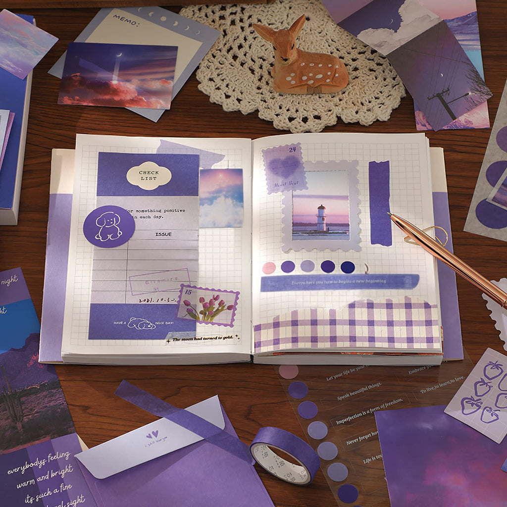 Aesthetic scrapbook kit contents laid out on a wooden desk, including a notebook, stickers, washi tape, and decorative paper.