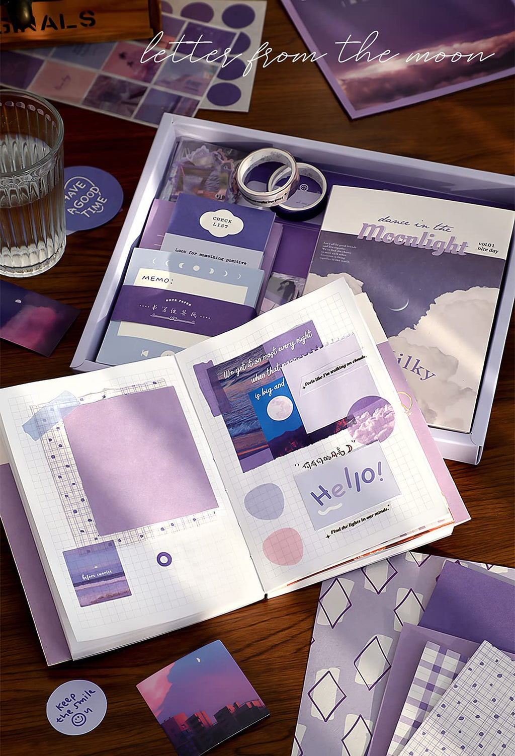 Aesthetic scrapbook kit contents laid out on a wooden table, including a notebook, stickers, washi tape, and decorative paper.
