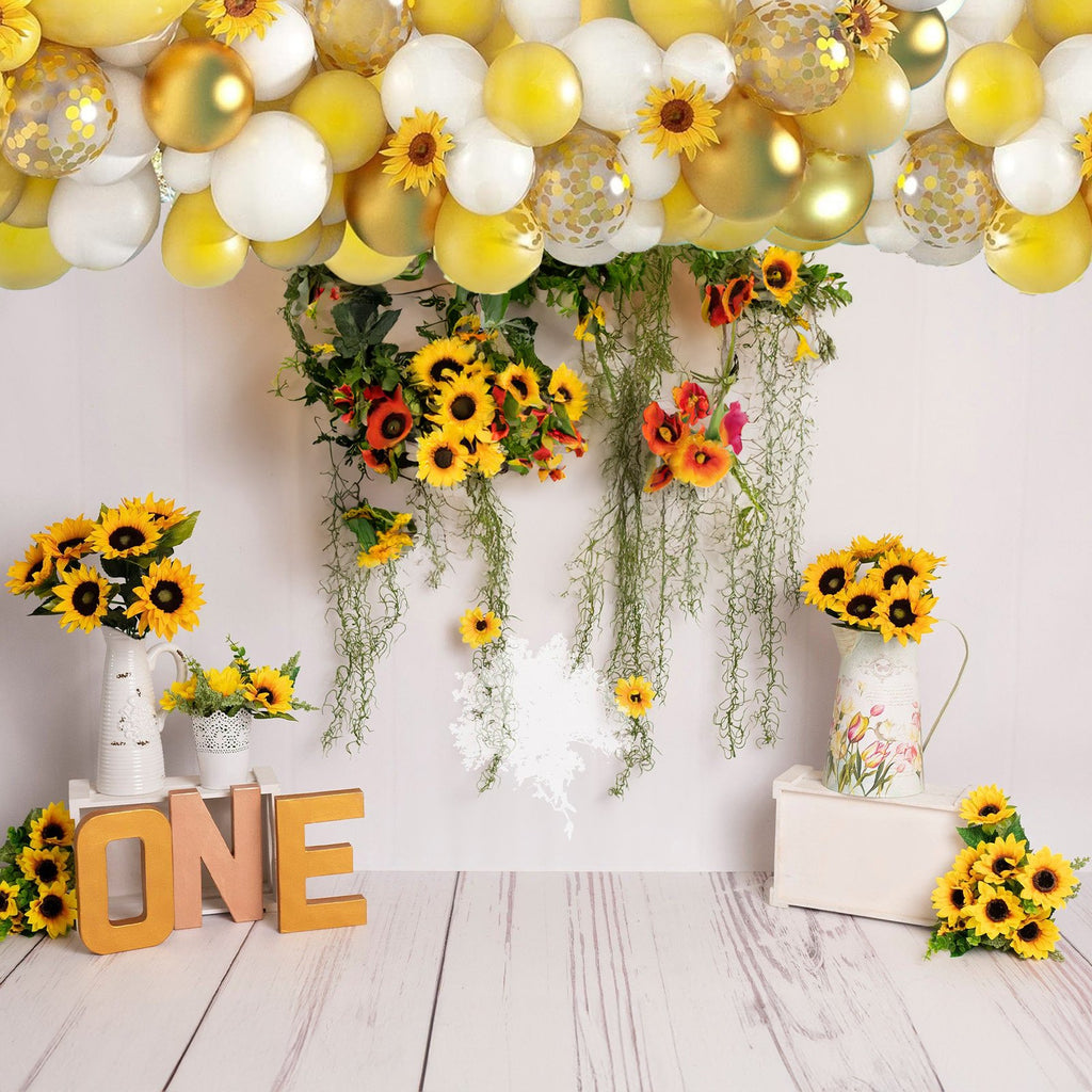 Balloon arch with sunflowers and decorative letters spelling ONE for a first birthday backdrop