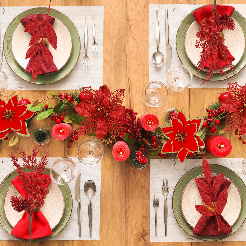 Christmas table setting with red glitter poinsettias, berry branches, candles, and place settings.
