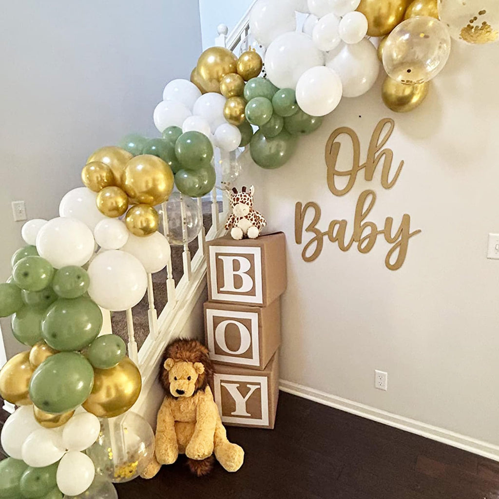 Balloon garland in sage green, gold, and white with confetti balloons, arranged on a staircase with stuffed animals and 'Oh Baby' decor.
