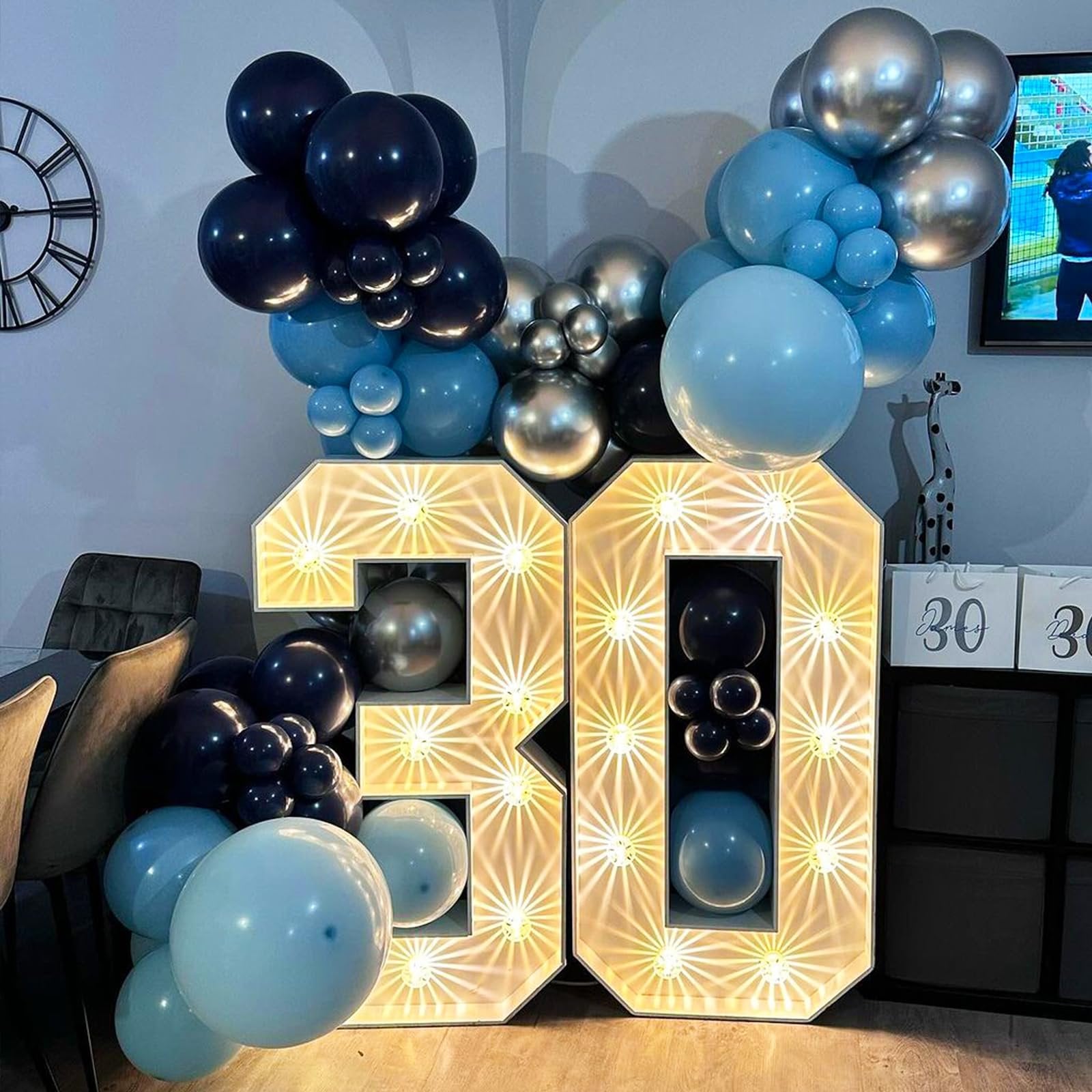 Illuminated number 30 decoration with blue, navy, and silver balloons for a party.