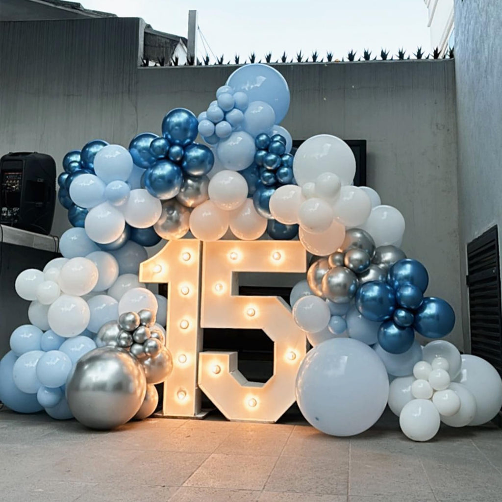 Illuminated number 15 decoration surrounded by blue, silver, and white balloons