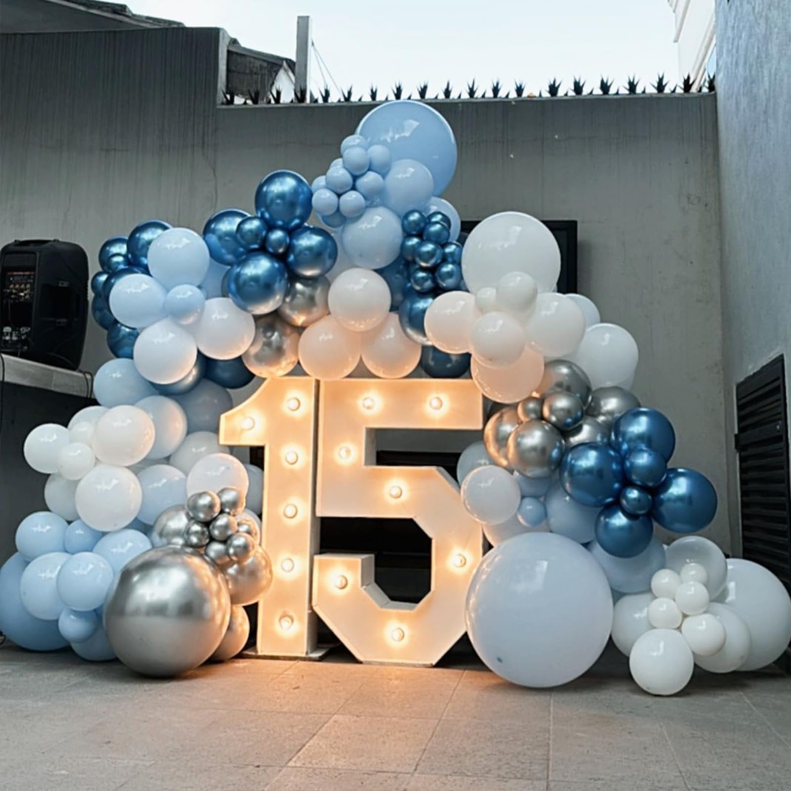 Illuminated number 15 decoration surrounded by blue, silver, and white balloons