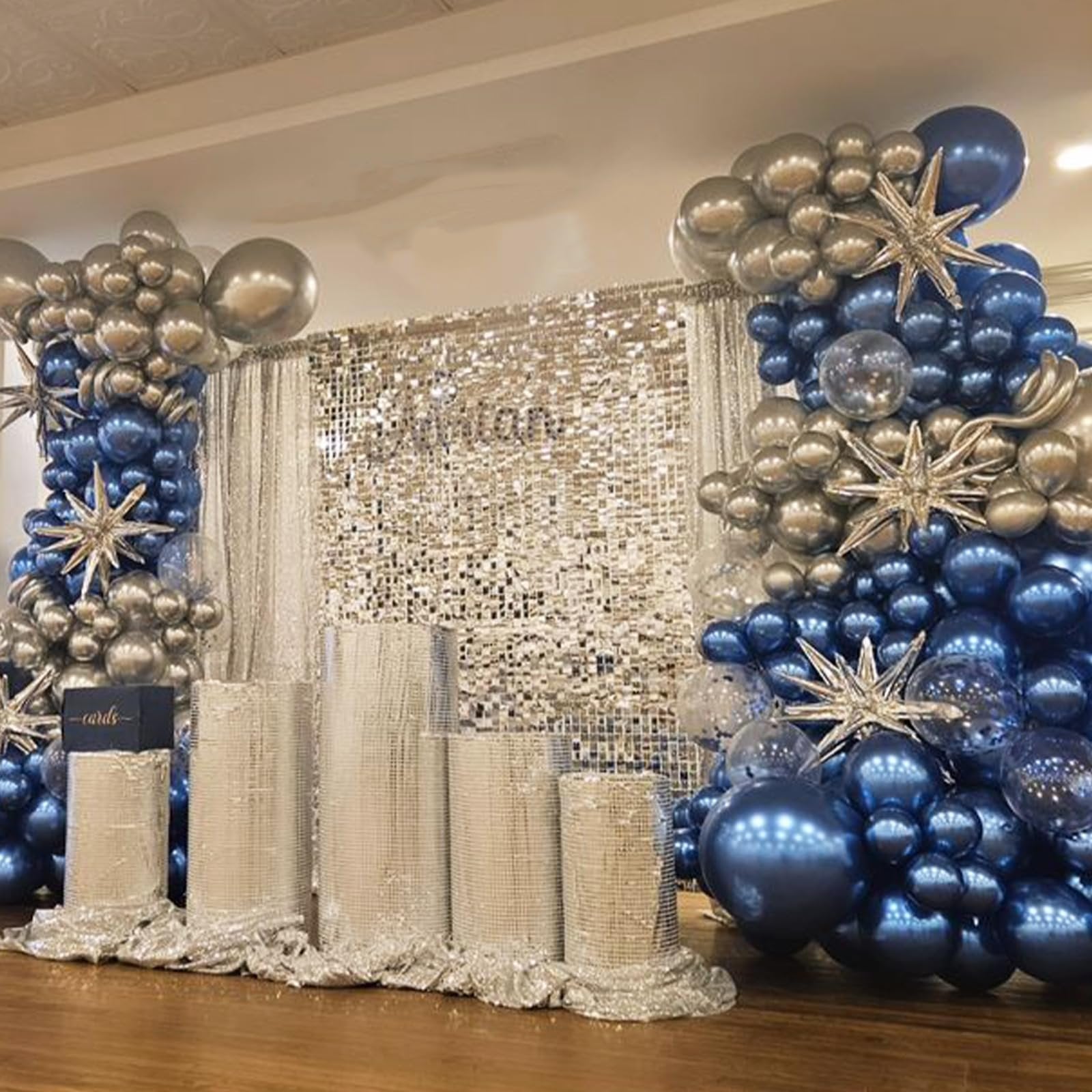 Blue and silver balloon arch with star accents and a sequin backdrop, set up for an event.