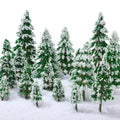 Assortment of miniature green pine trees with white snow flocking, arranged in a snowy landscape against a white background.