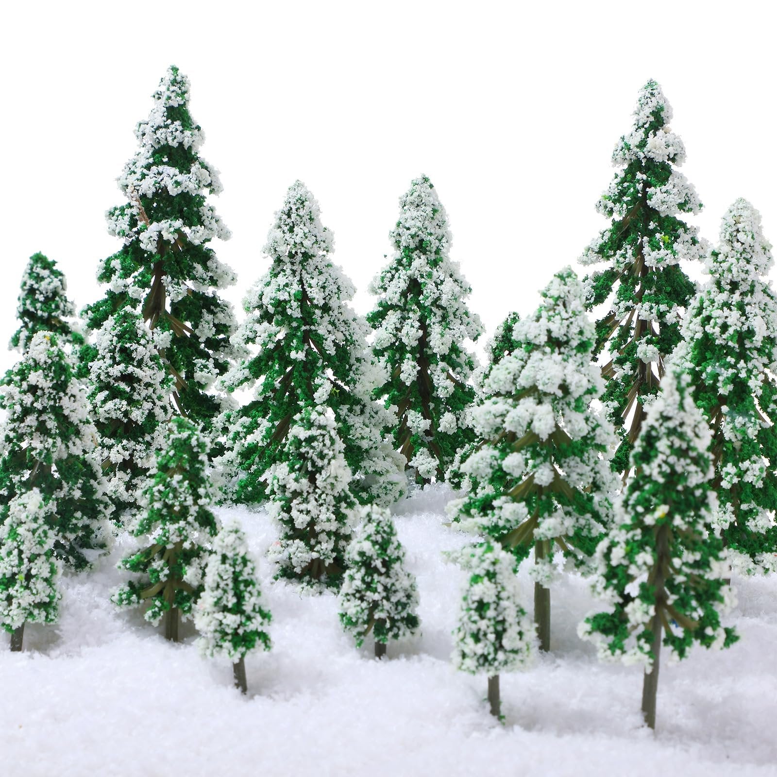 Assortment of miniature green pine trees with white snow flocking, arranged in a snowy landscape against a white background.
