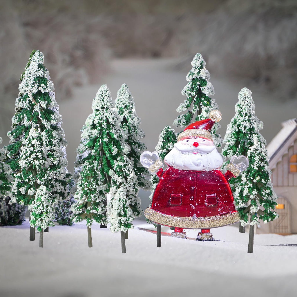 Miniature snowy pine trees and a Santa Claus figure in a winter village scene.