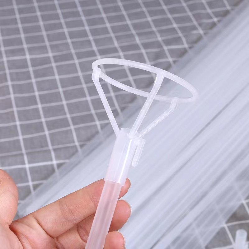 Hand holding a clear plastic balloon stick holder with a grid pattern background