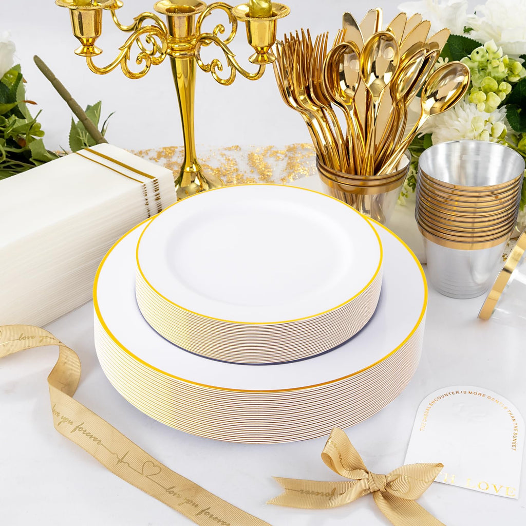 Stack of white and gold rimmed dinner plates and salad plates with gold cutlery and cups, a gold candelabra, and white napkins.
