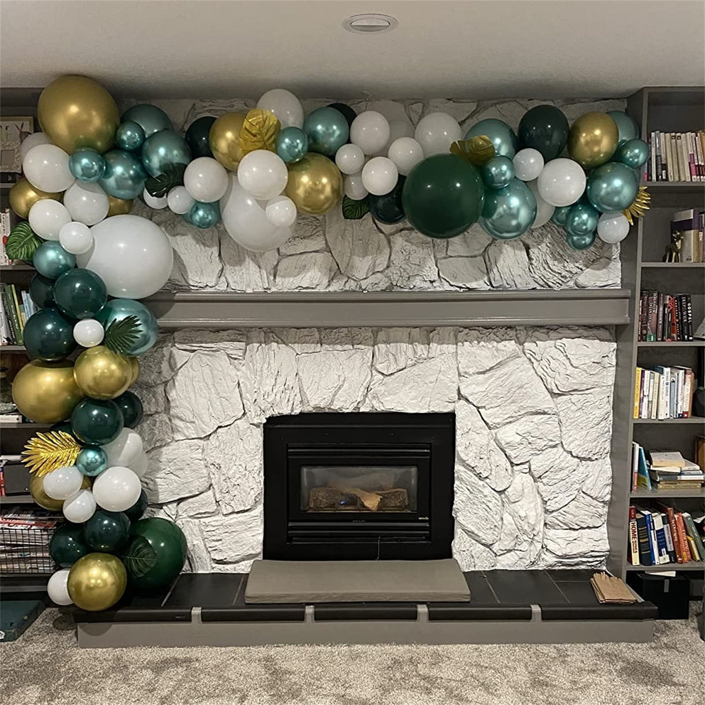 Balloon garland in dark green, gold, and white draped over a stone fireplace mantel