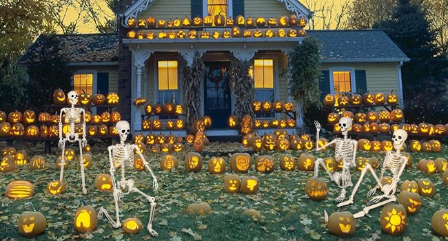 Halloween decorated house with carved pumpkins and skeletons on lawn