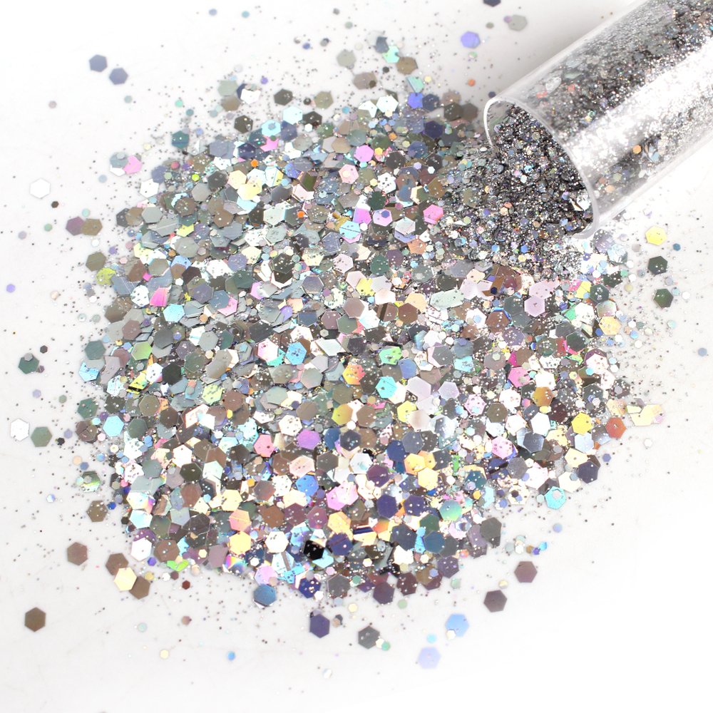 Silver chunky holographic glitter spilling from a clear tube onto a white surface.