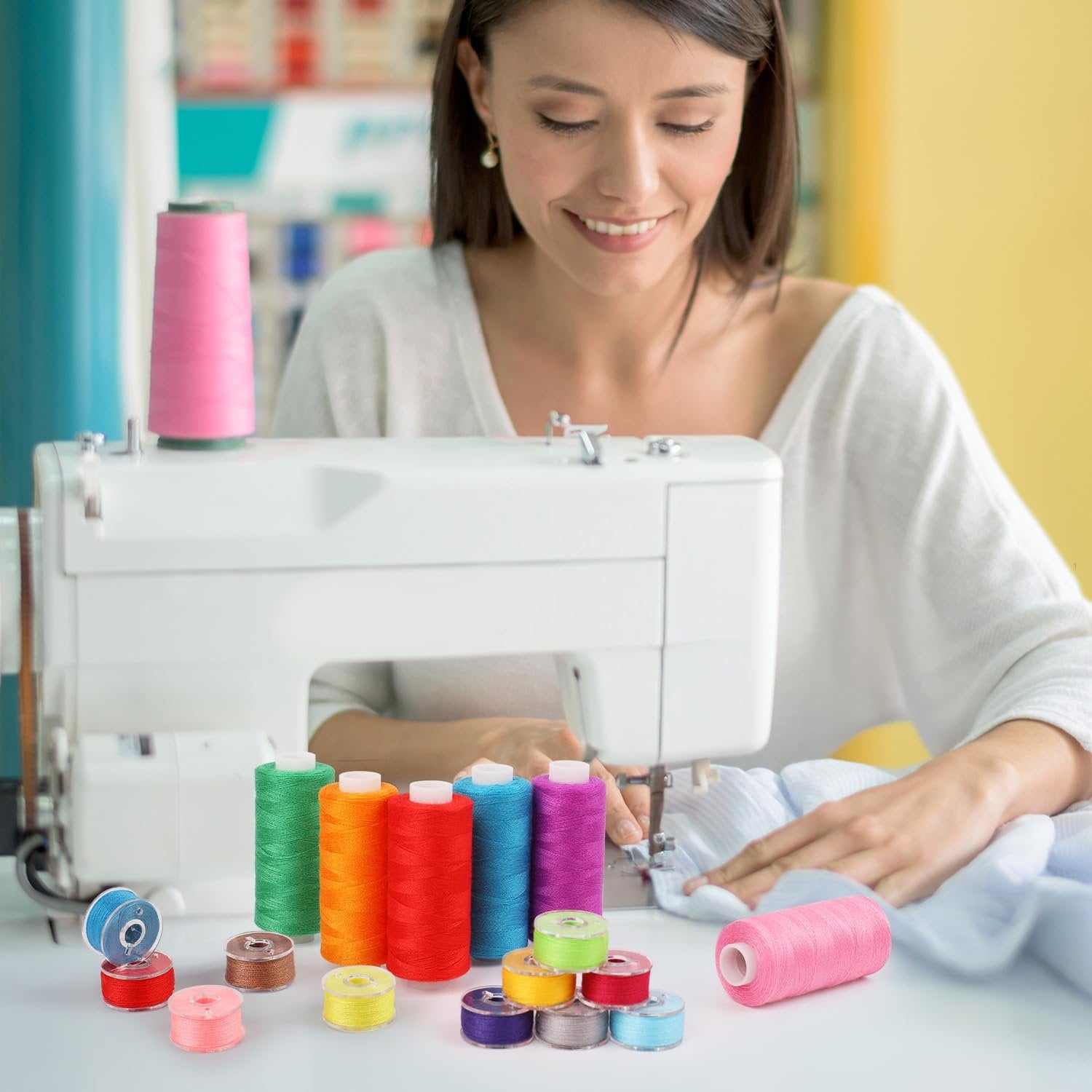 Woman sewing with colorful thread spools and bobbins arranged on a table