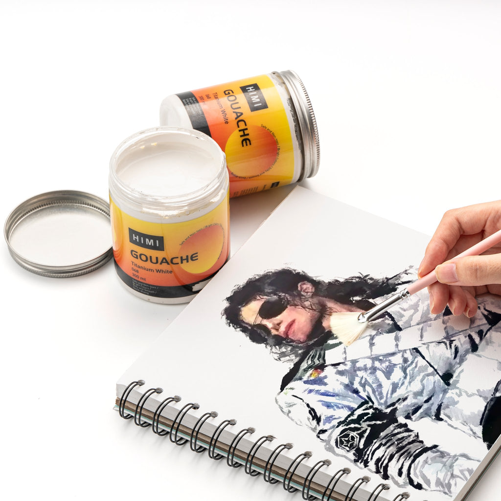 Two jars of white gouache paint and a sketchbook with a portrait being painted by a hand holding a brush.