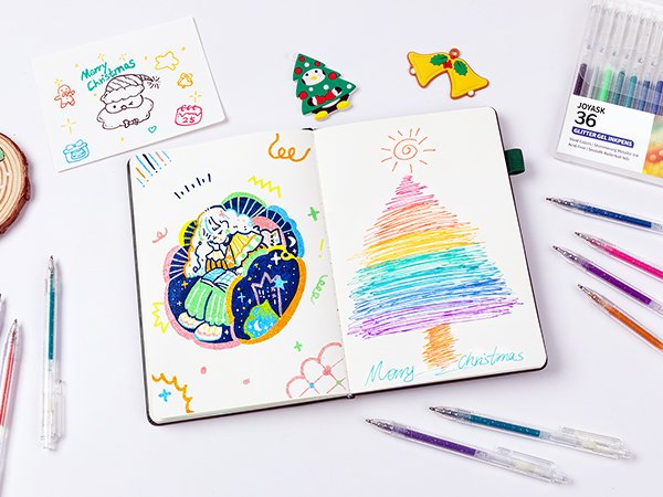 Open notebook with Christmas drawings and glitter gel pens scattered around, a box of pens in the background.