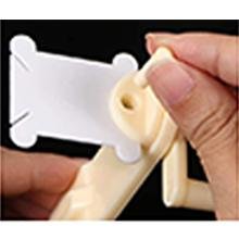 Close-up of hands winding embroidery floss onto a plastic bobbin using a white winder tool.