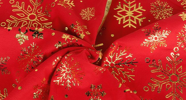 Red Christmas tree skirt with gold snowflake and dot print, close-up view