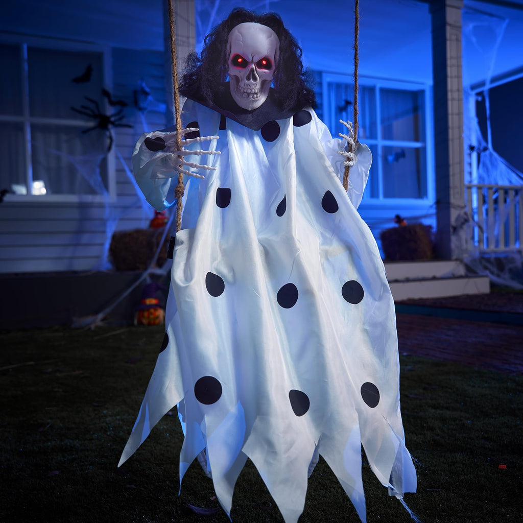 Hanging clown skeleton Halloween decoration with red glowing eyes and a white polka dot costume, swinging from rope outdoors at night.