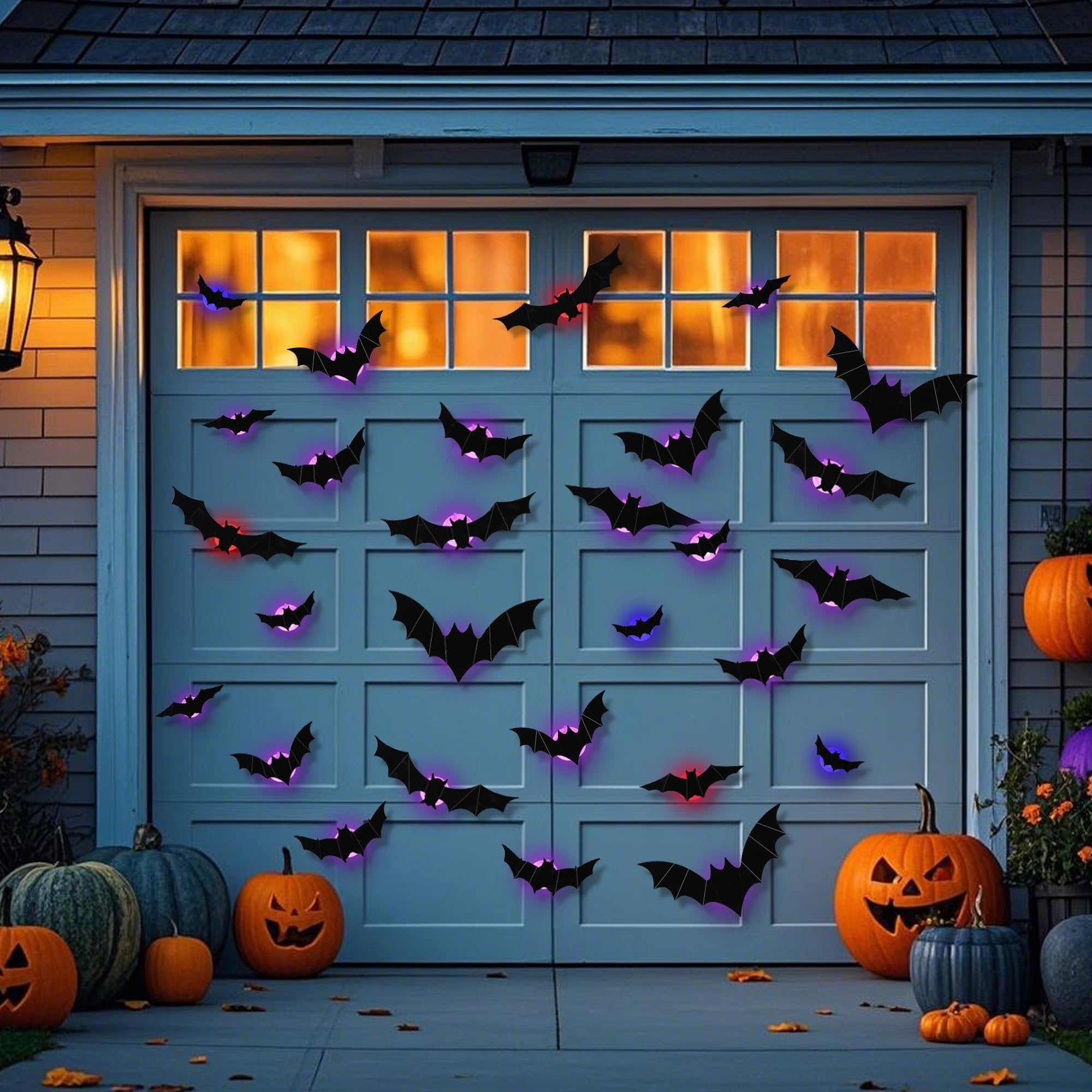 Halloween bat decorations with purple and red lights on a garage door with pumpkins and a lantern