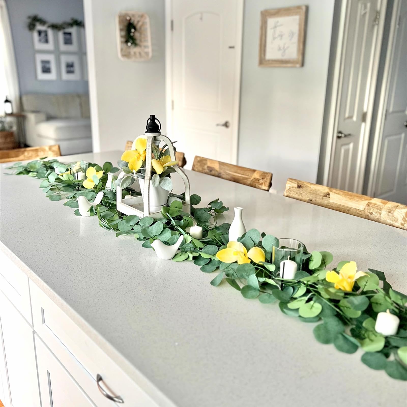 Artificial eucalyptus garland with yellow flowers and white birds arranged on a kitchen island