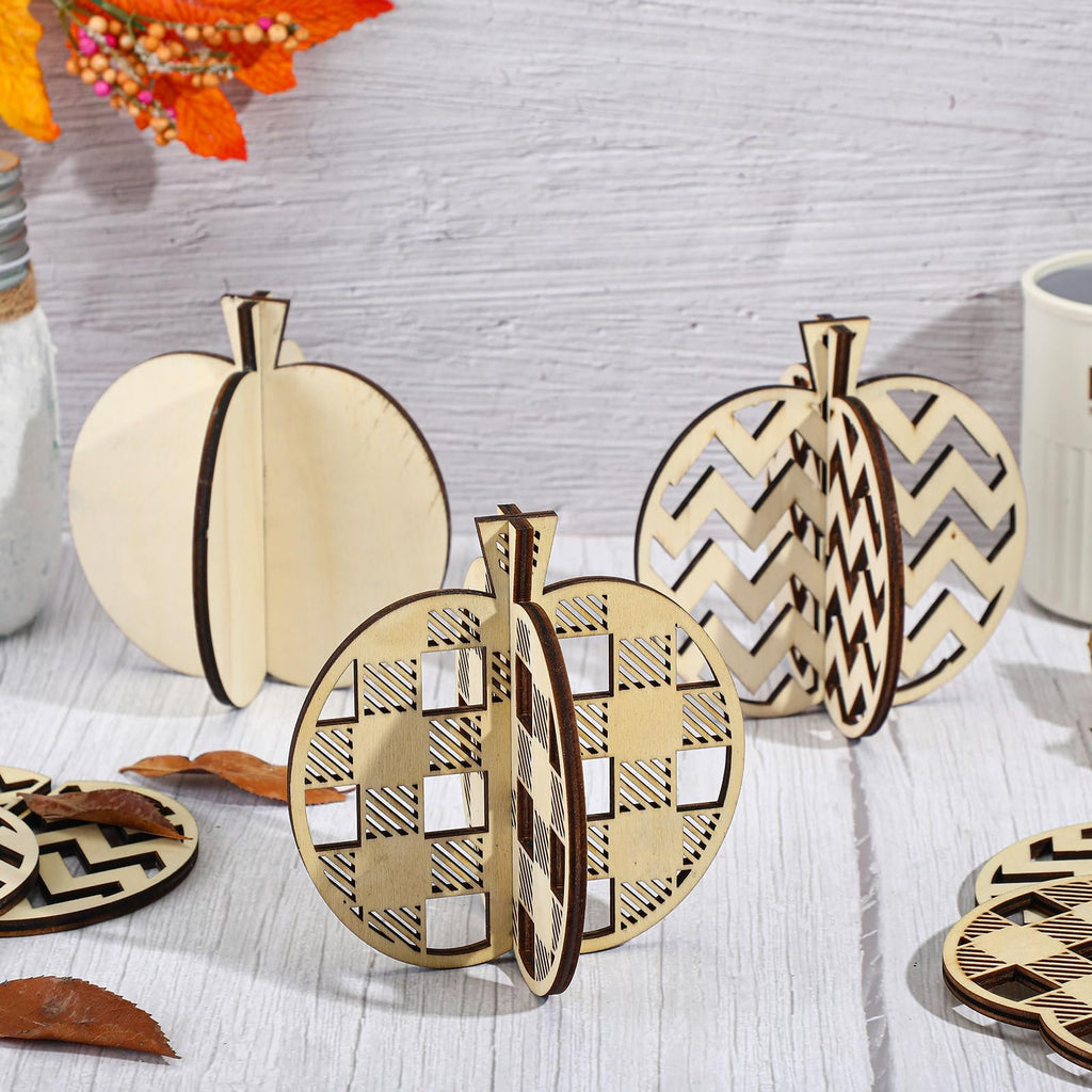 Three wooden pumpkin craft cutouts with different patterns displayed on a white wooden surface, with autumn leaves and a jar in the background.