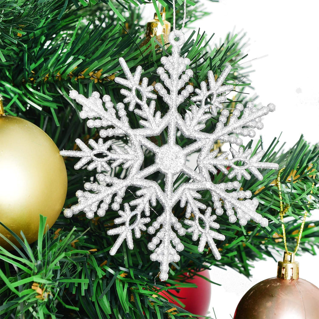 Silver glitter snowflake ornament hanging on a Christmas tree with gold and red ornaments.