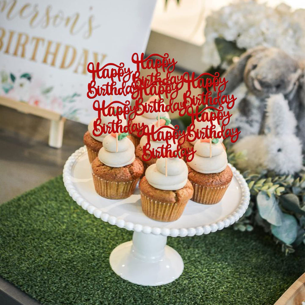 Red glitter 'Happy Birthday' cupcake toppers inserted into frosted cupcakes on a white cake stand, with a blurred background.