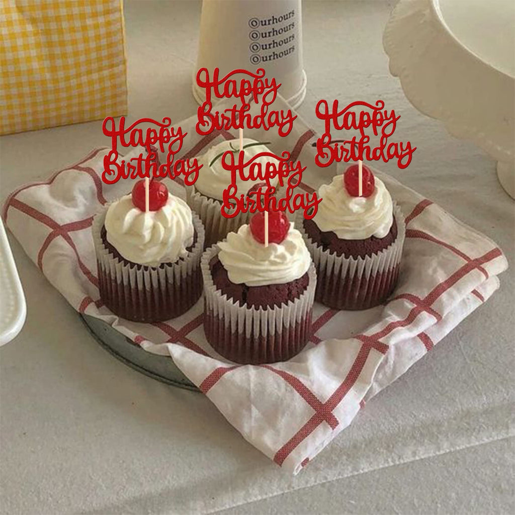 Four red velvet cupcakes with white frosting and red cherry on top, decorated with red glitter 'Happy Birthday' cake toppers.