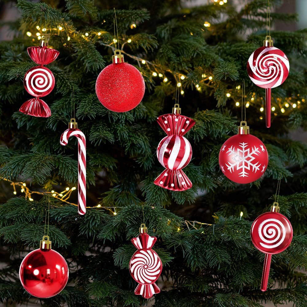 Red and white Christmas ornaments in candy, lollipop, candy cane, and ball shapes hanging on a decorated tree.
