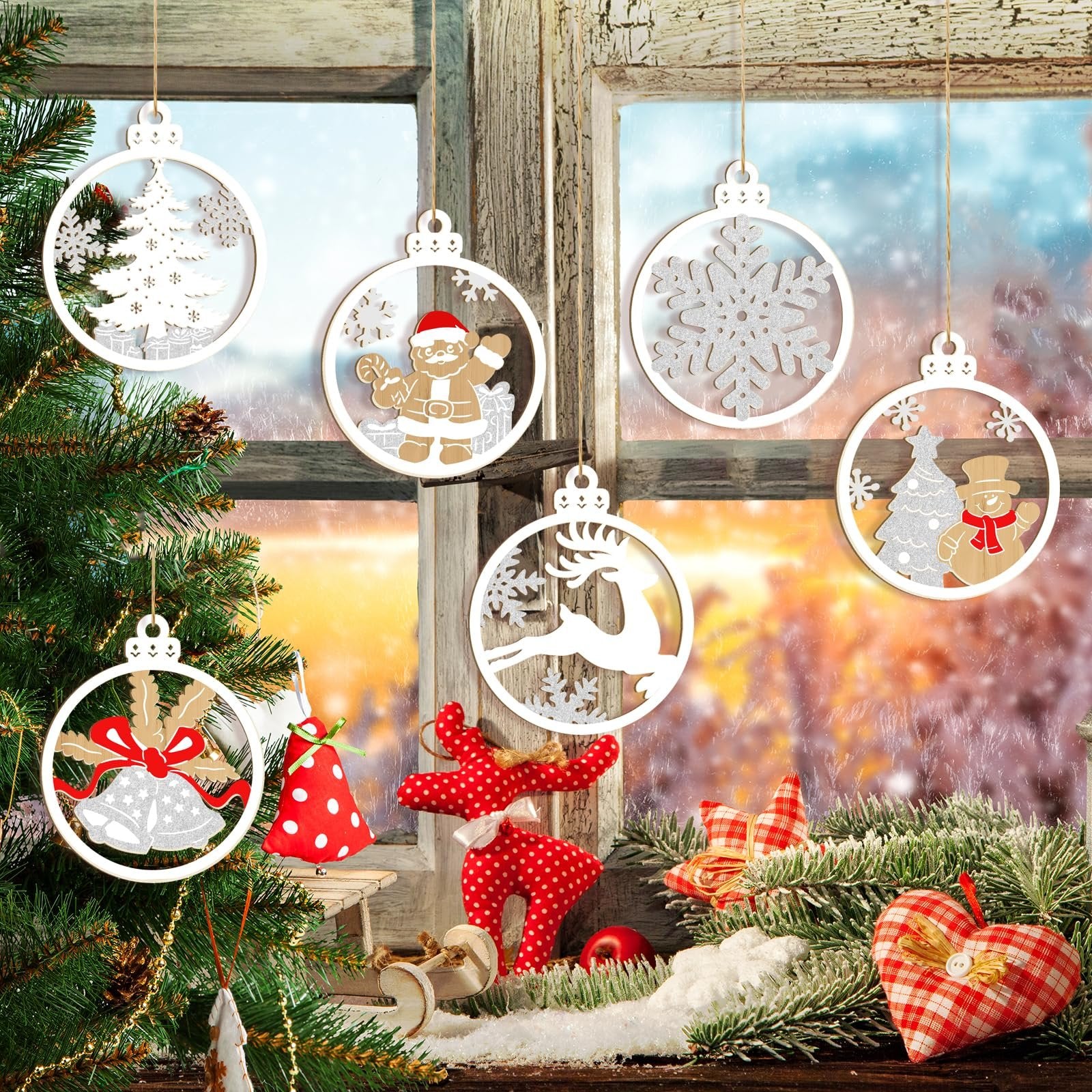 Assortment of unfinished wooden Christmas ornaments hanging in a window with a snowy winter scene outside.