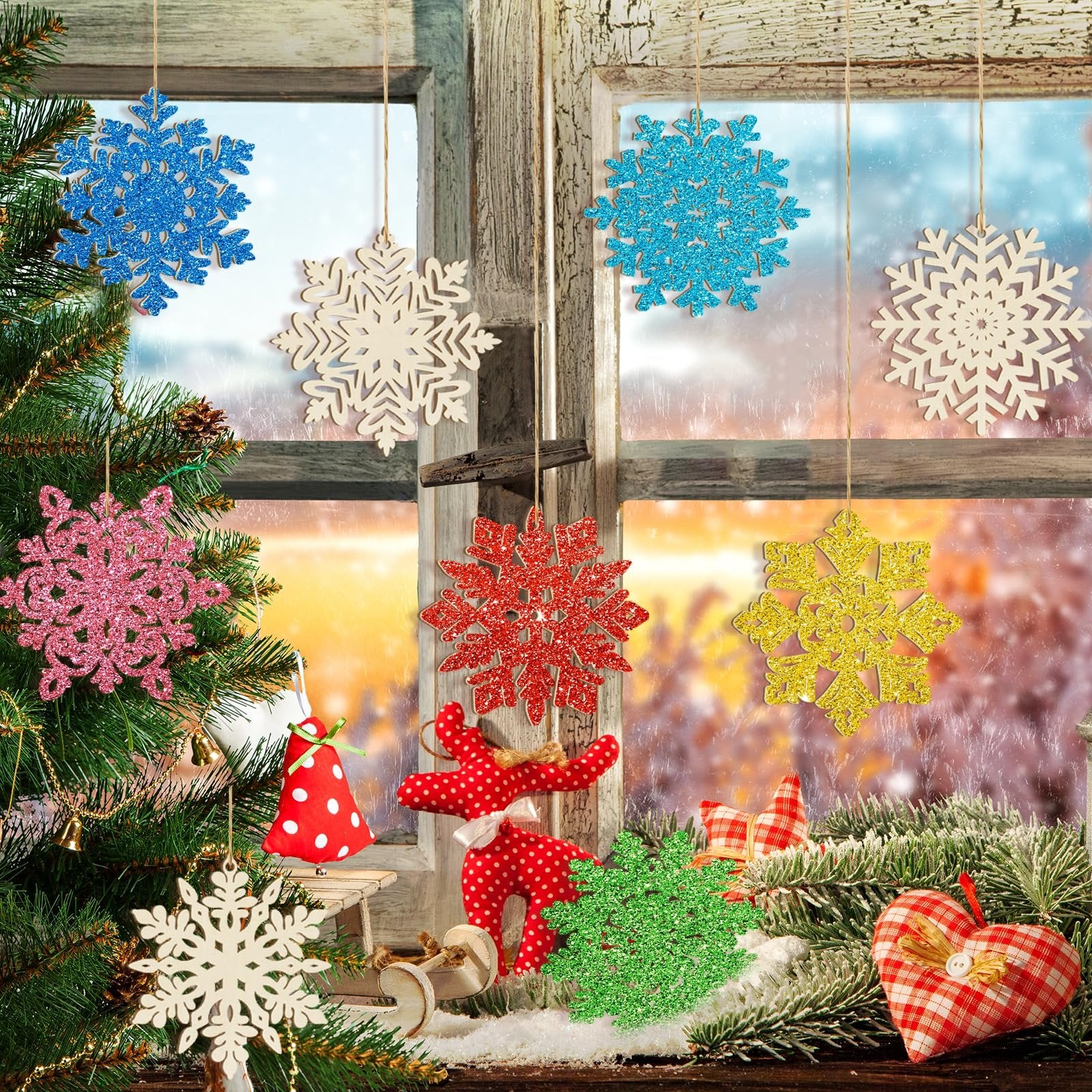 Assorted glitter and unfinished wooden snowflake ornaments hanging in a window with a Christmas tree and festive decorations