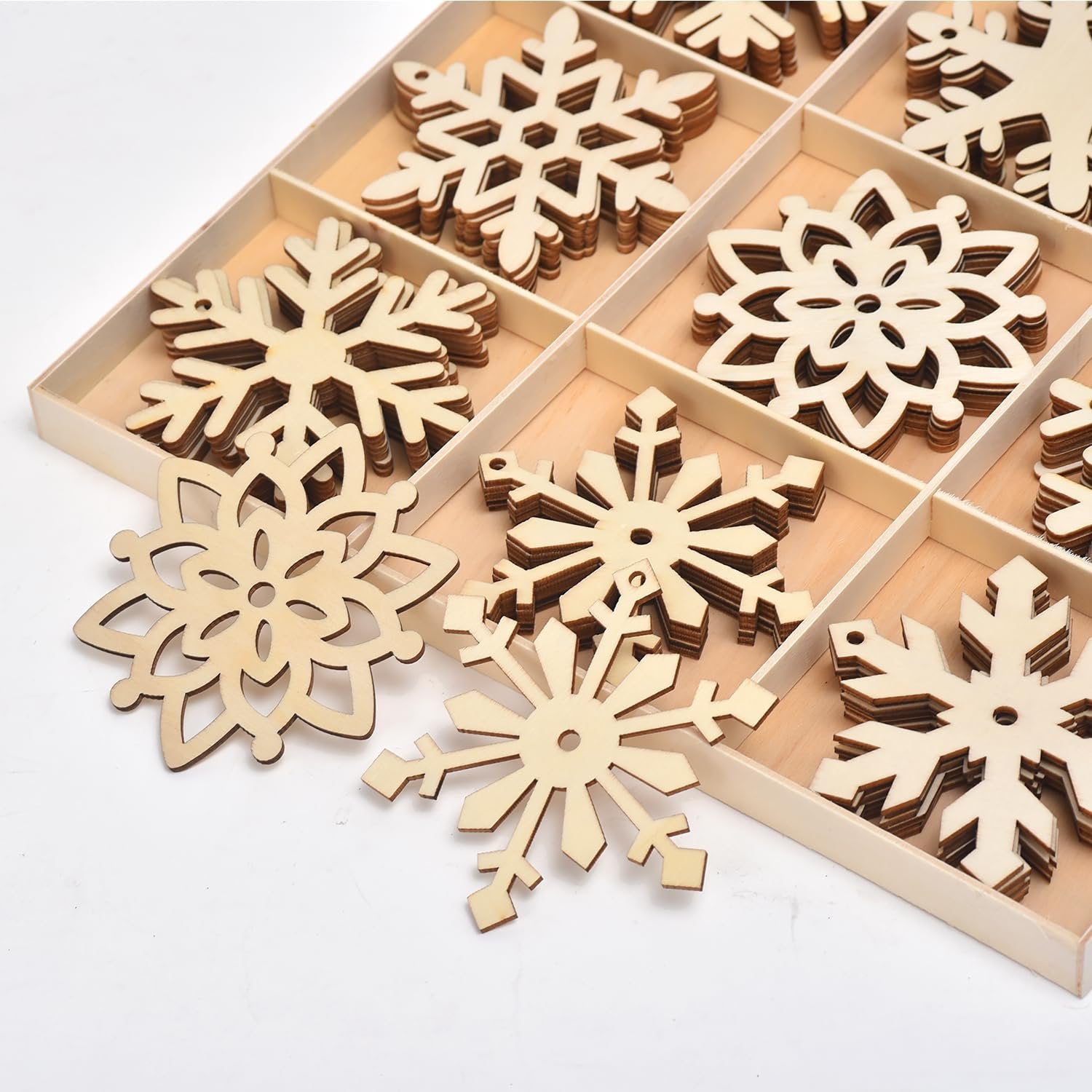 Unfinished wooden snowflake ornaments in a divided wooden box, close-up view