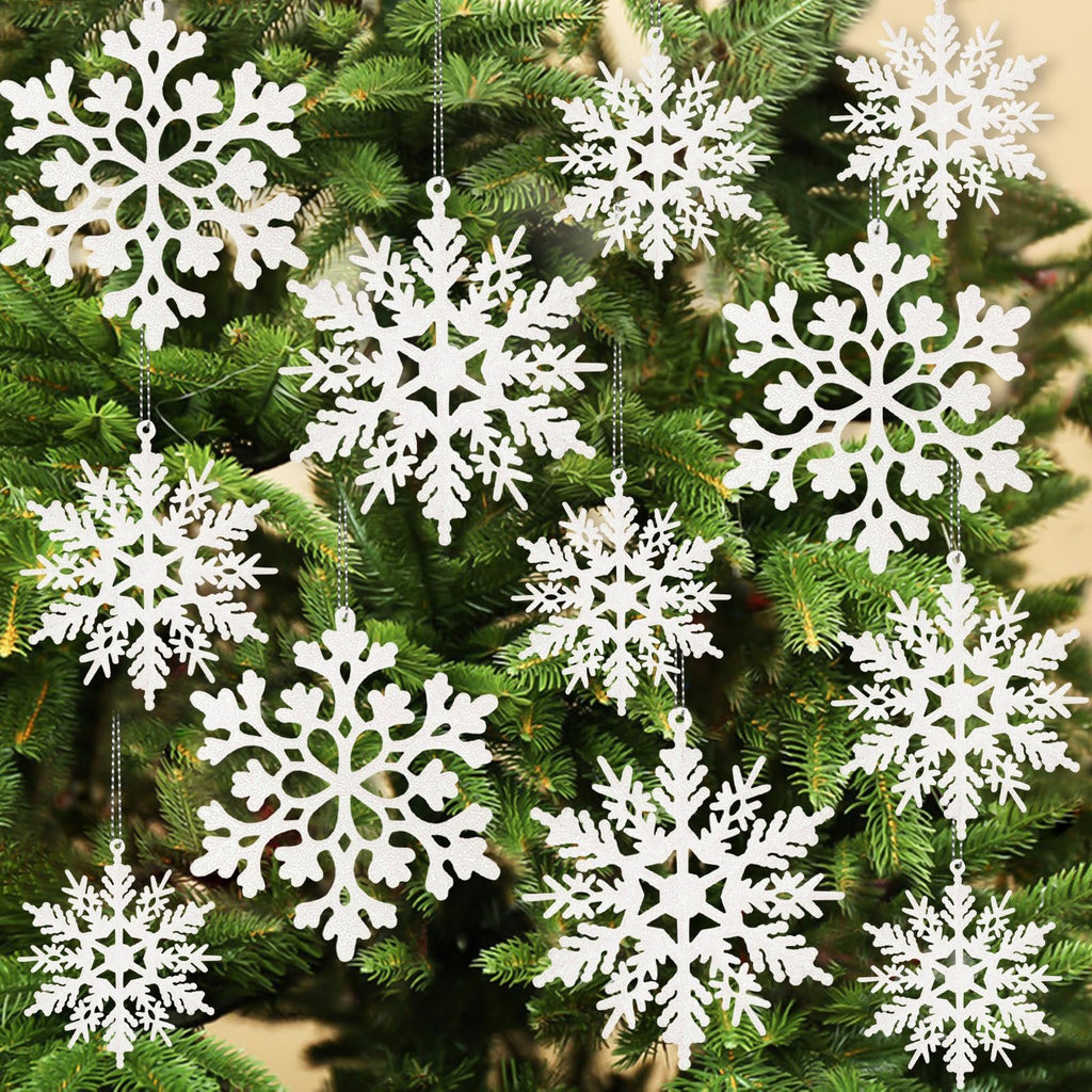 White glitter snowflake ornaments hanging on a Christmas tree, showing various sizes and patterns.