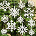 White glitter snowflake ornaments hanging on a Christmas tree, showing various sizes and patterns.