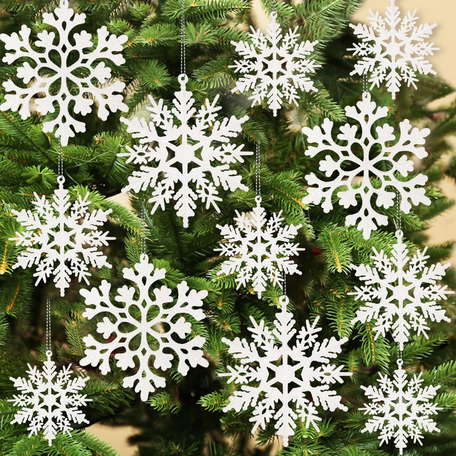 White glitter snowflake ornaments hanging on a Christmas tree, showing various sizes and patterns.