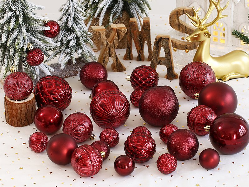 Wine red shatterproof Christmas ball ornaments in various sizes and styles arranged with festive decor.