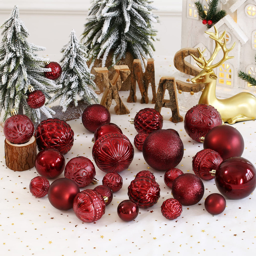 Wine red shatterproof Christmas ball ornaments in various sizes and styles arranged with festive decor.
