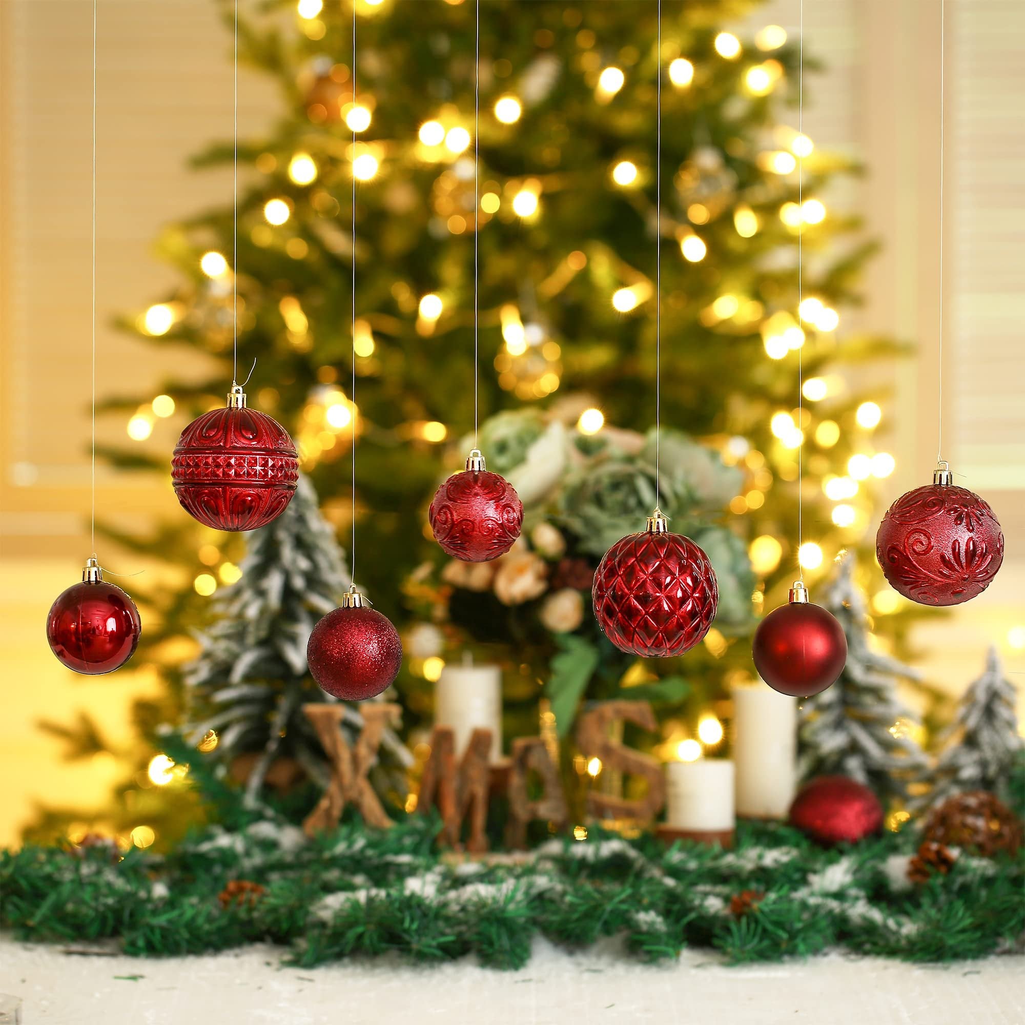 Wine red shatterproof Christmas ball ornaments hanging in front of a decorated Christmas tree