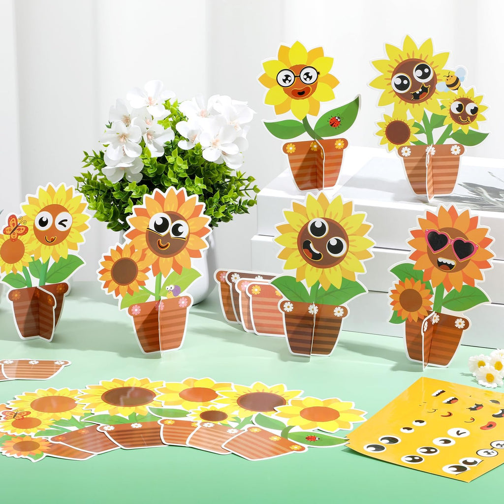 DIY sunflower craft kit pieces laid out with cartoon faces, pots, and stickers, next to a vase of white flowers.