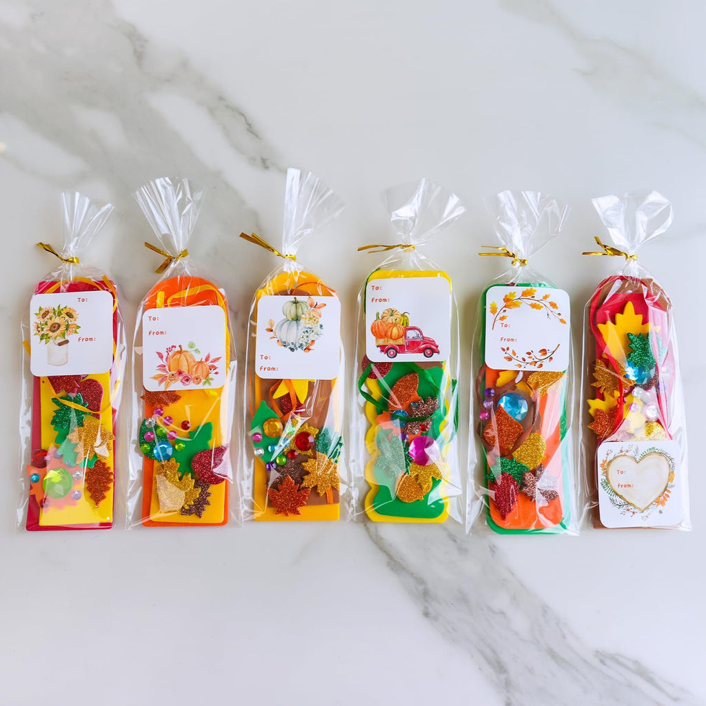 Six fall craft kits for kids, each in a clear plastic bag with a gift tag, containing glitter foam leaf shapes and gems.
