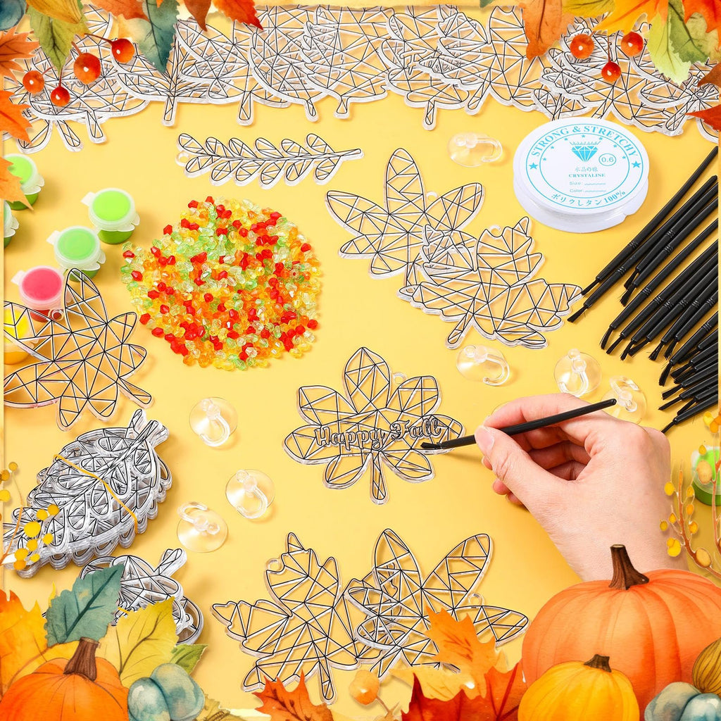Pumpkin leaf suncatcher paint kit contents laid out on yellow background with autumn leaves border