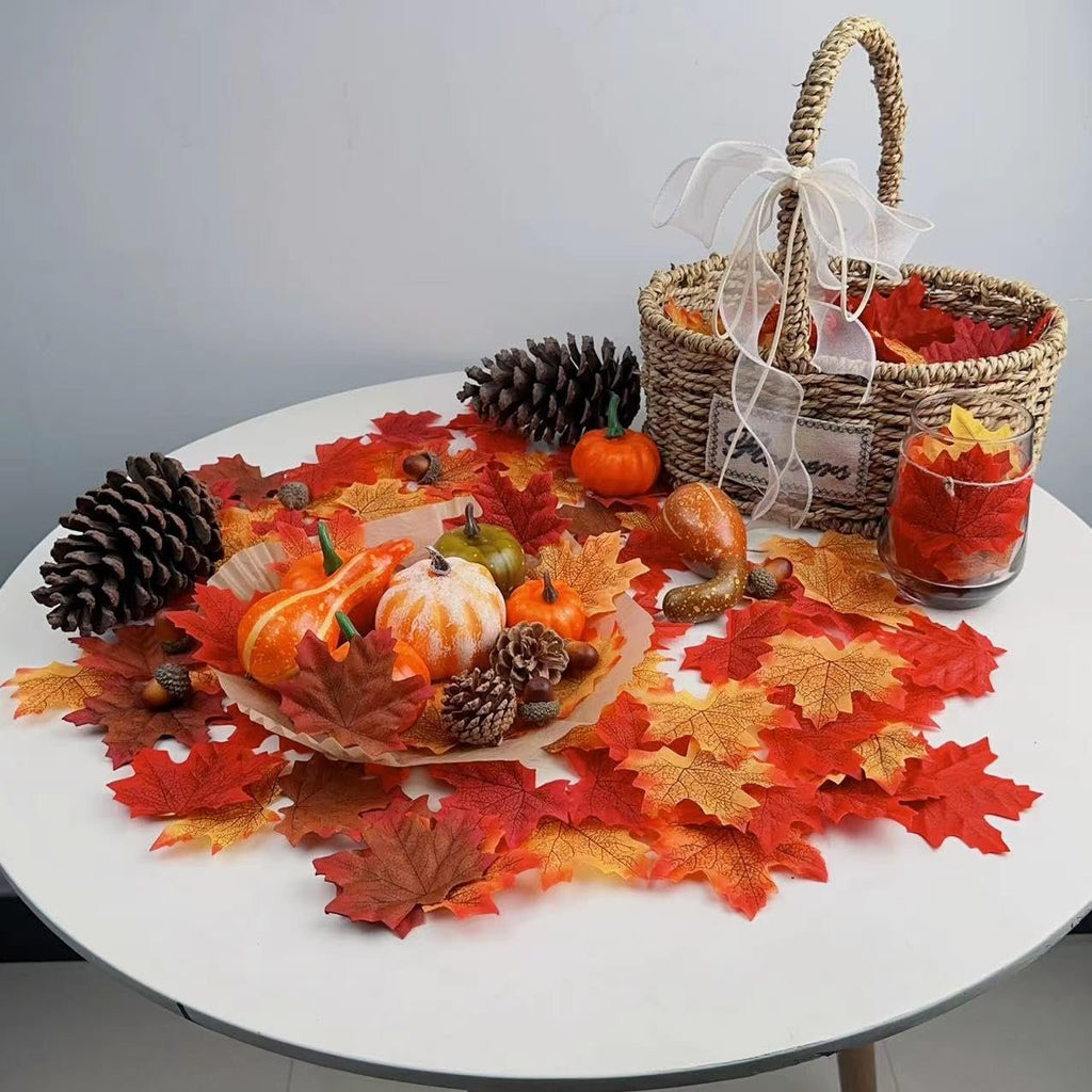 Autumn table decor with artificial maple leaves, mini pumpkins, gourds, pinecones, and acorns scattered around a basket.