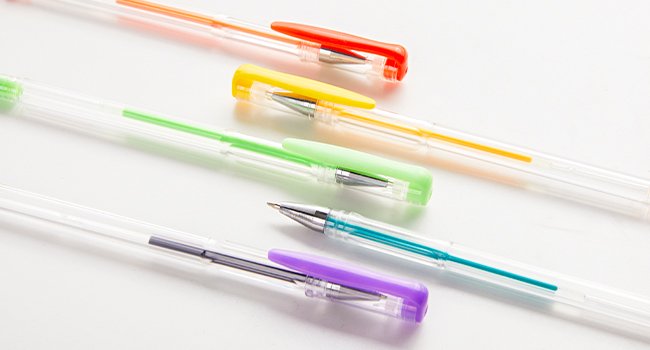 Assortment of colorful gel pens with clear barrels and colored caps, laid out diagonally on a white background.