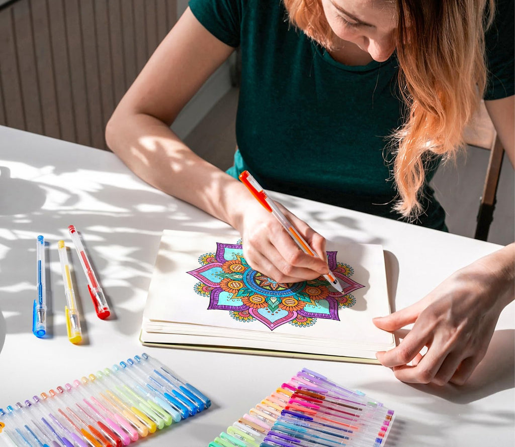 Woman coloring a mandala with gel pens, multiple pen sets visible