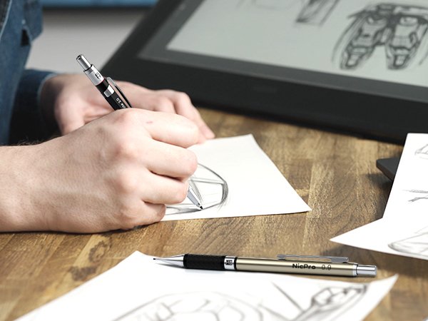 Person sketching with a mechanical pencil in front of a digital drawing tablet, another pencil on desk