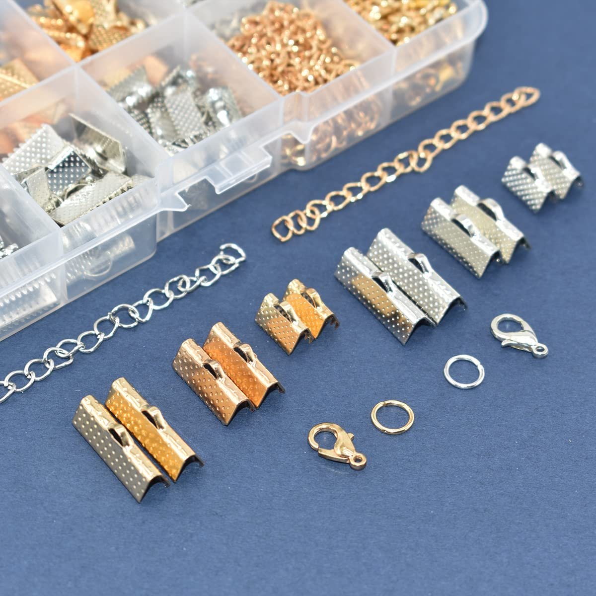 Jewelry making kit components including chains, clasps, jump rings, and ribbon end crimps in a clear organizer box.